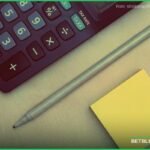 Calculadora e caderno com a conta para converter odds decimais, fracionárias e americanas